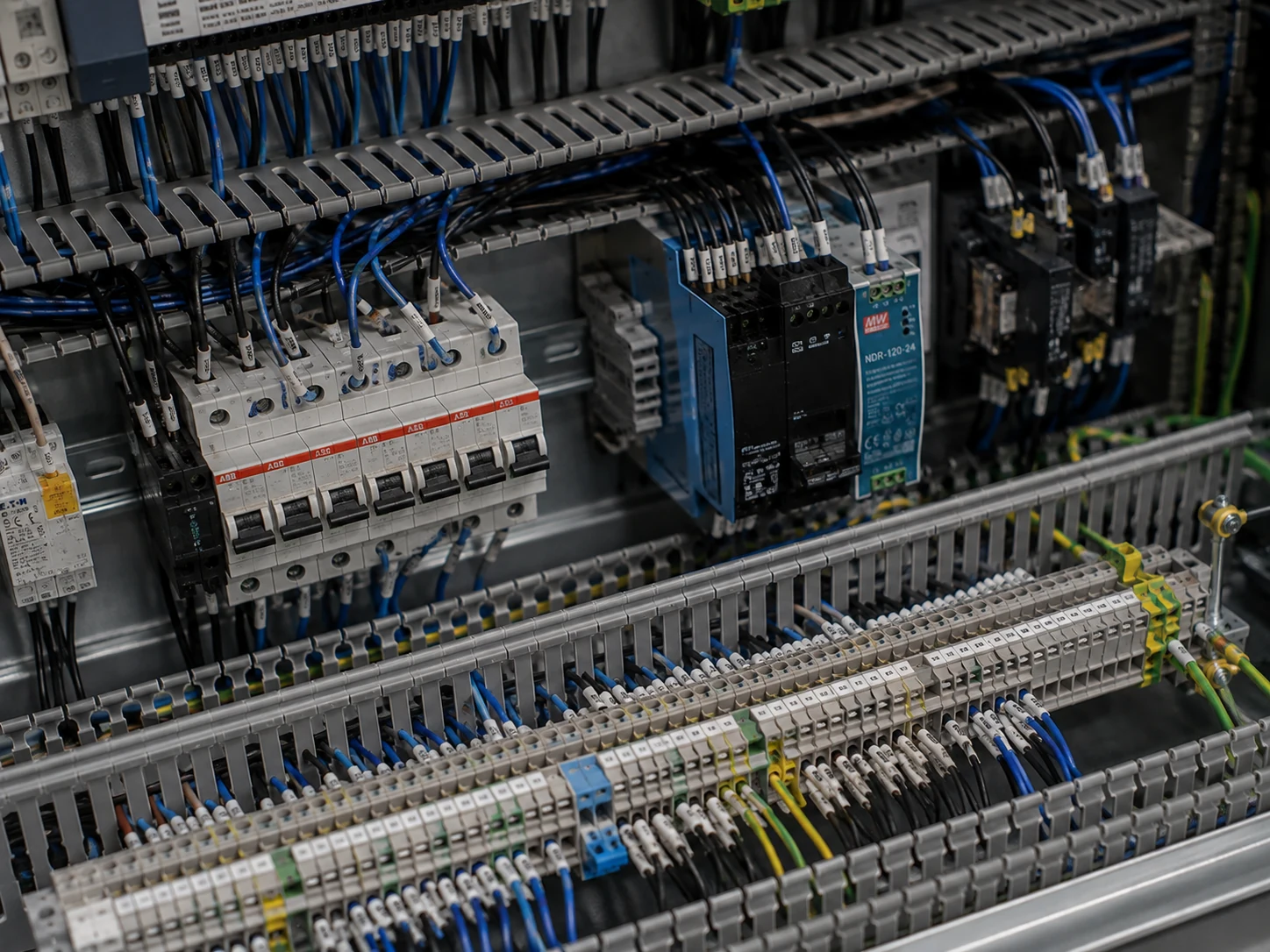 Detalle del montaje de un cuadro eléctrico: protecciones en carril DIN, fuente, canaleta y bornes con conductores identificados