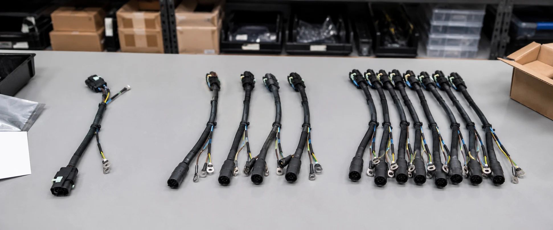 Prototipos y series cortas de cableado sobre una mesa de trabajo: una unidad suelta, un grupo de cuatro y un lote mayor